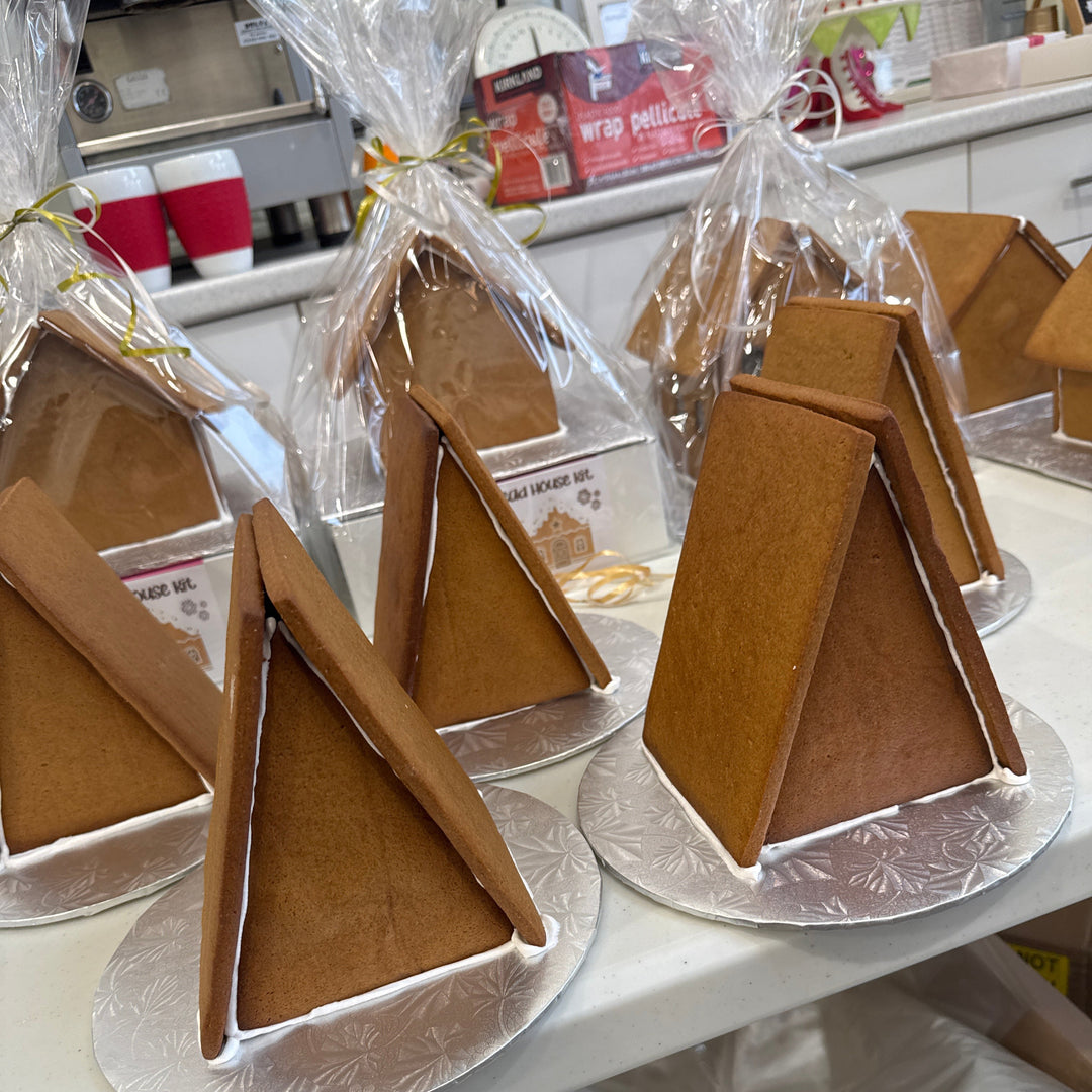 Assorted gingerbread houses in various shapes and sizes displayed on a table, decorated with white icing and candy decorations.