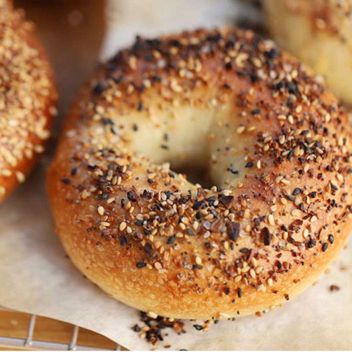 Bagels with sesame seeds and everything seasoning on a cooling rack.